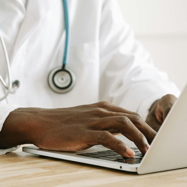 a podiatrist using a laptop to create a personalized care plan for a patient