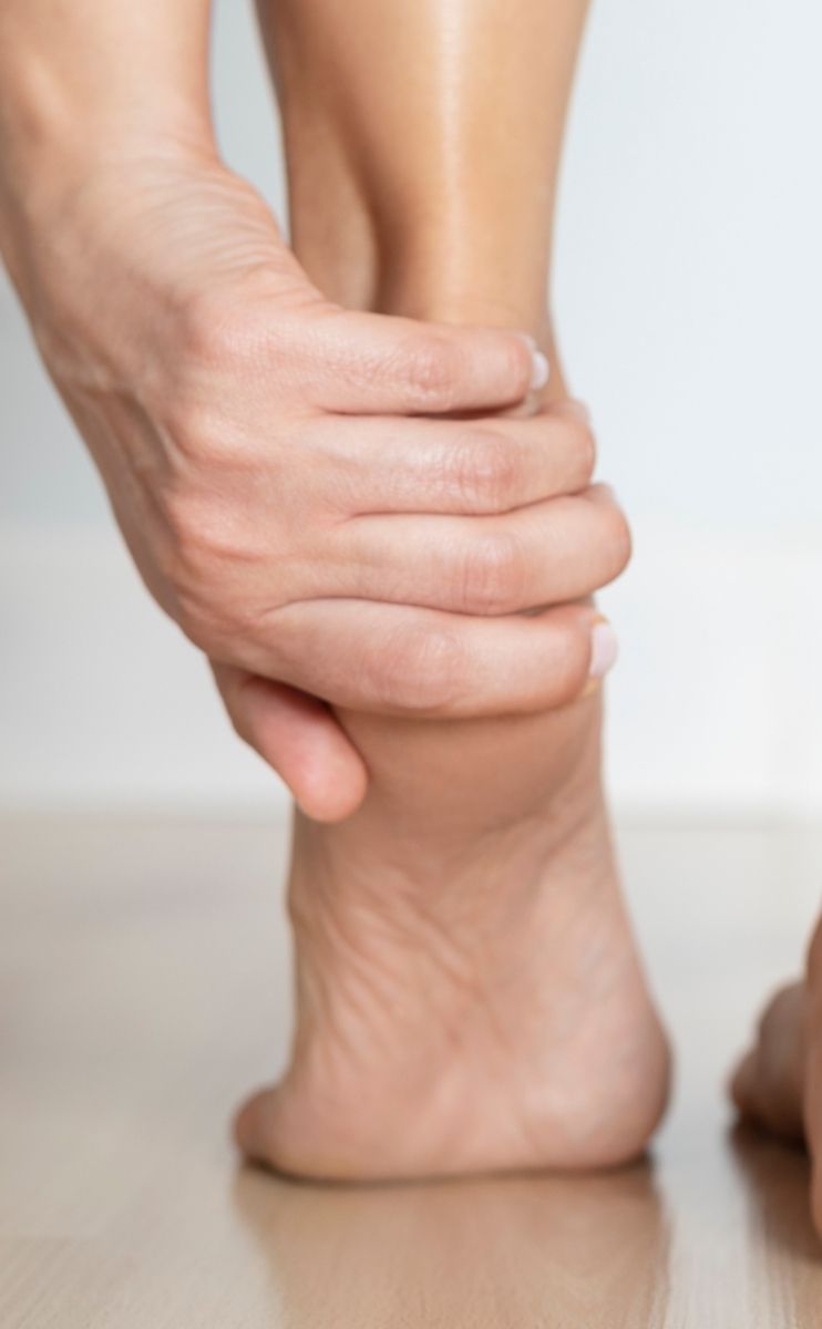 a woman holding her heel affected by bone spurs a woman holding her heel affected by bone spurs