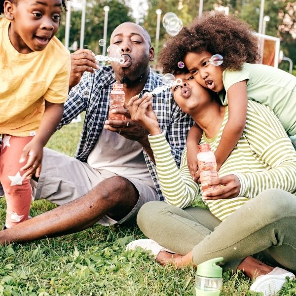 family playing outside while blowing bubbles
