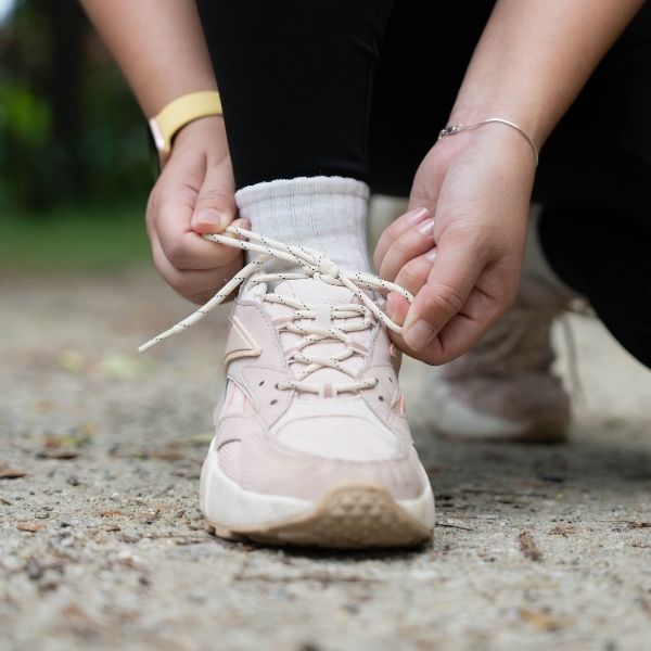 photo of a person tying a shoe containing a custom orthotic insert