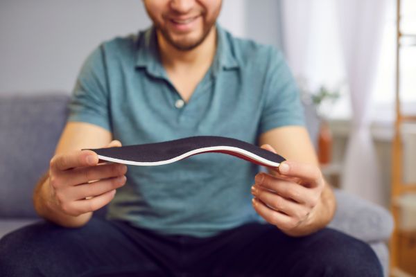 photo of a smiling man holding up a custom orthotic
