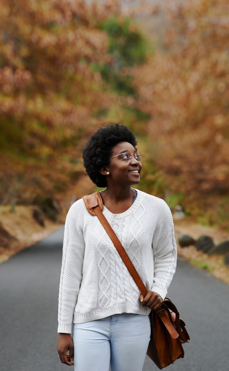 photo of a woman walking along a roadway through the Carolina woods during fall