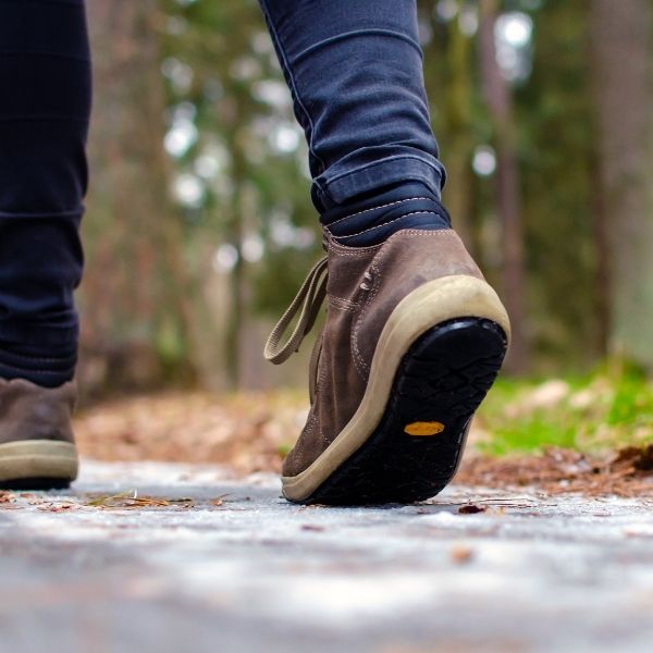 photo of feet walking along a roadway through some woods