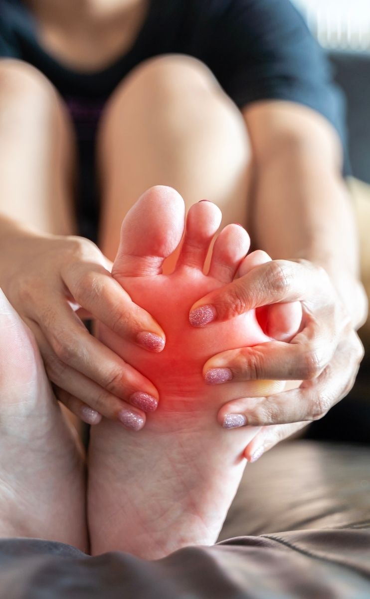 woman holding her foot experiencing metatarsalgia woman holding her foot experiencing metatarsalgia